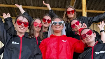 Frauen mit Herz-Sonnenbrillen, fröhlich posierend.