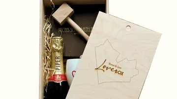 Gift box with champagne, mug, and wooden mallet.