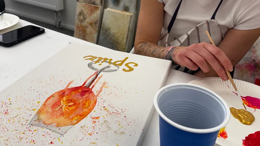 Person painting on canvas with bright colors.