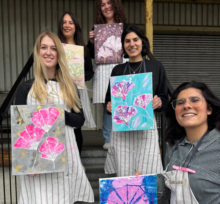 Five people displaying colorful paintings outside.