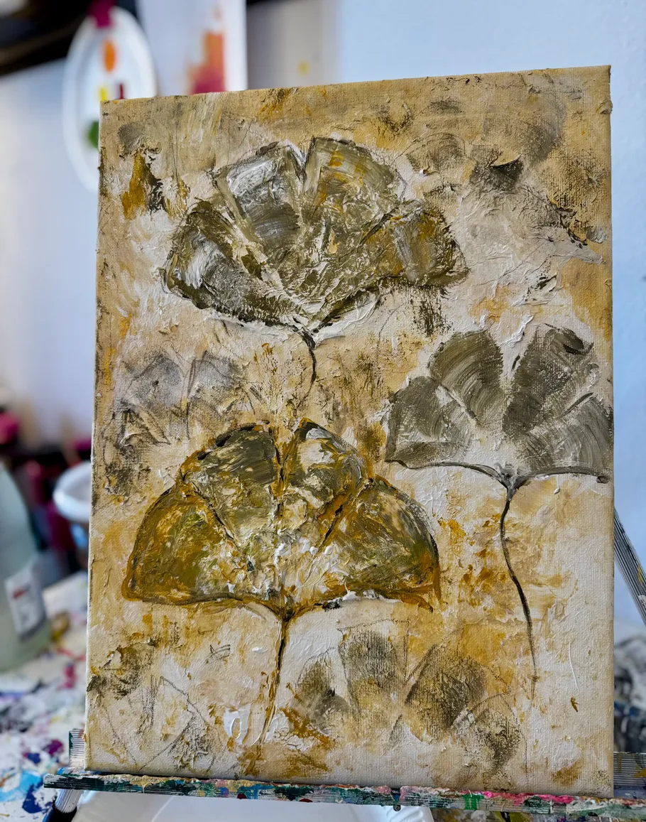 Textured painting of abstract leaves on easel.