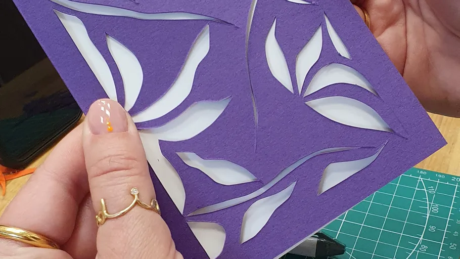 Hands holding purple paper cut-out design.