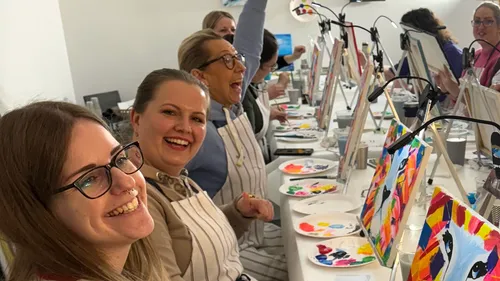 People painting at an art class table.