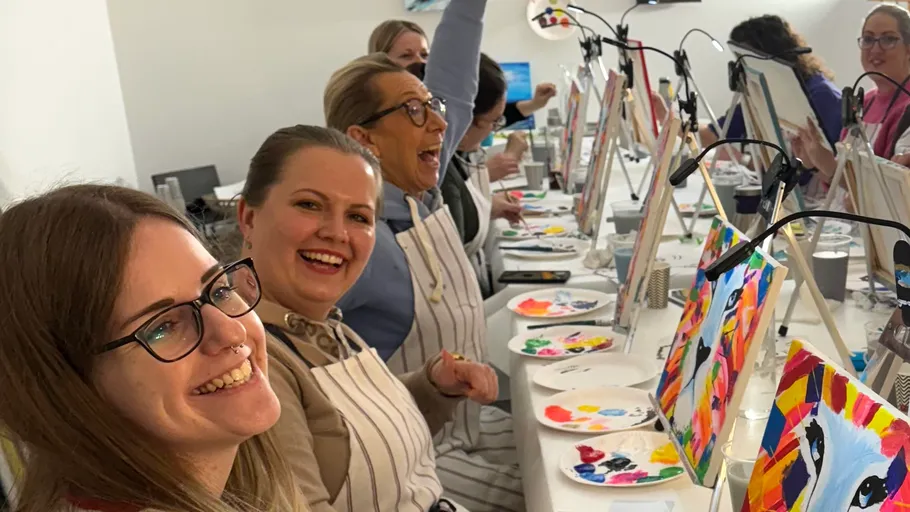 People painting at an art class table.