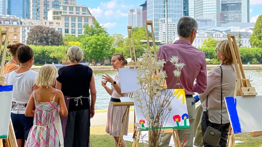 People painting outdoors near a river.