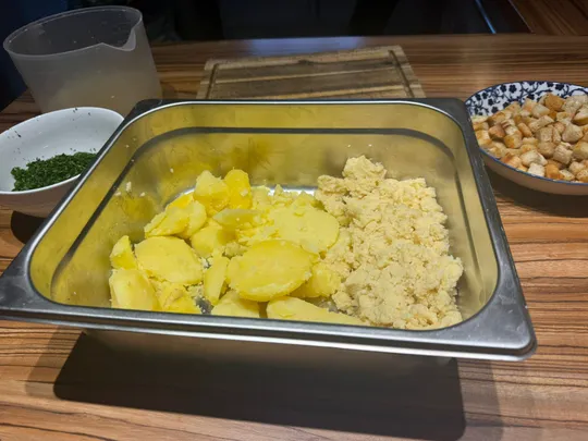 Potatoes and croutons on a wooden table.