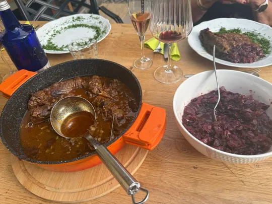 Cooked beef in sauce with red cabbage side.
