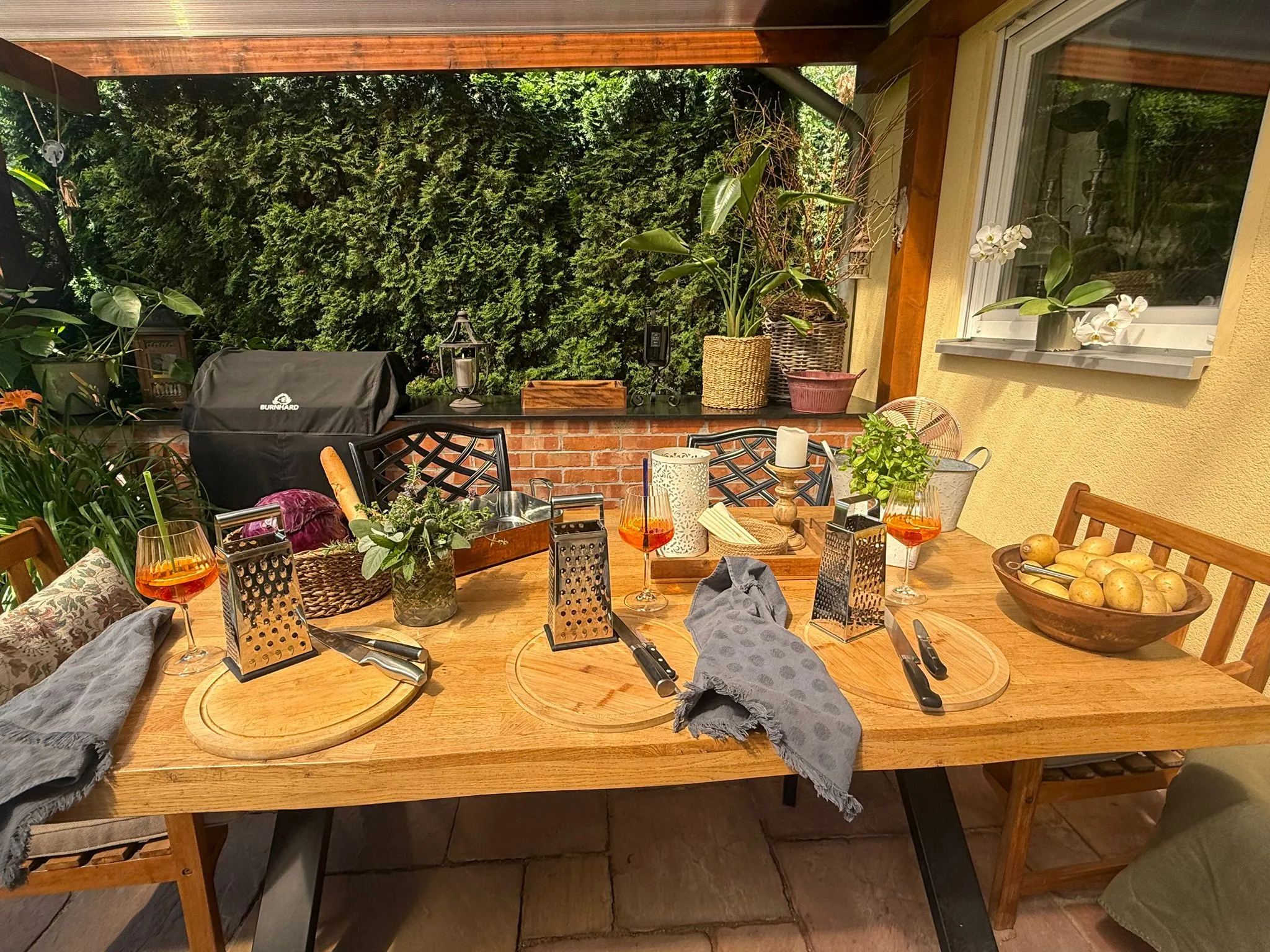 Gedeckter Gartentisch mit Reiben und Getränken.