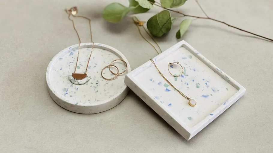 Schmuck auf Terrazzo-Tabletts mit Blättern.