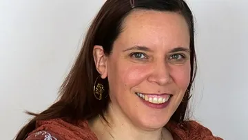 Woman smiling against a neutral background.