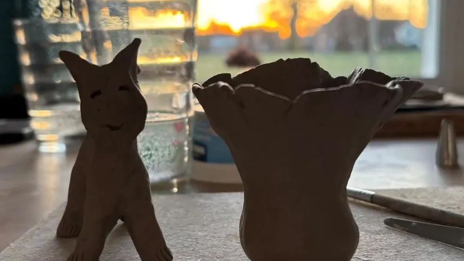 Tonfiguren auf Tisch, Sonnenuntergang draußen.