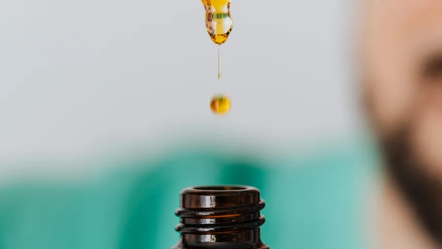 Dropper releasing liquid into a brown bottle.