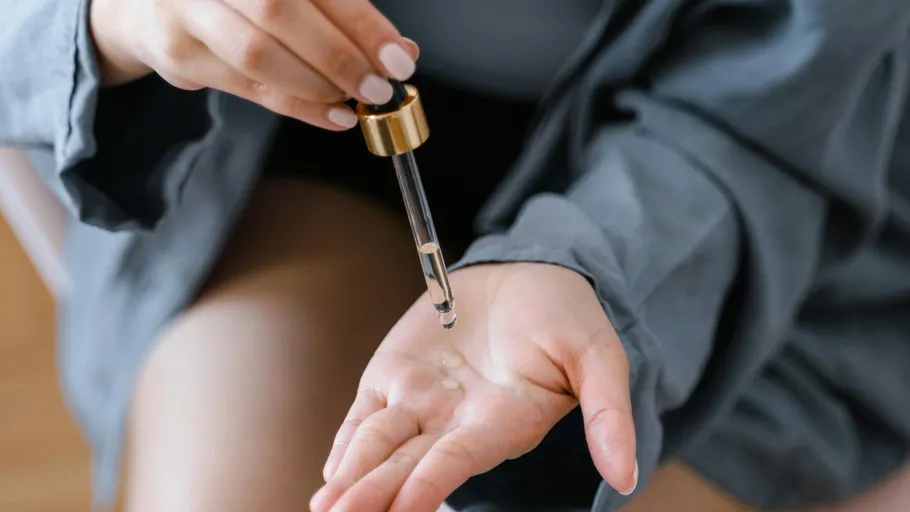 Person applying serum with dropper to hand.