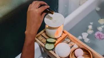 Hand adds oil to diffuser near bath.