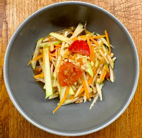 Green papaya salad in a gray bowl.