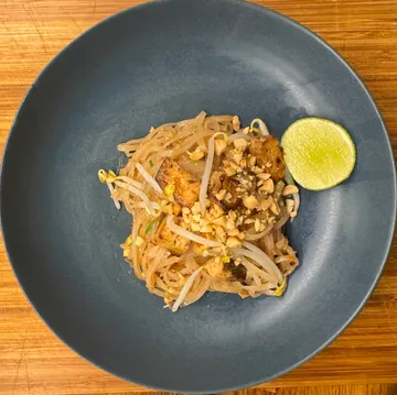Pad Thai mit Limette auf blauem Teller.