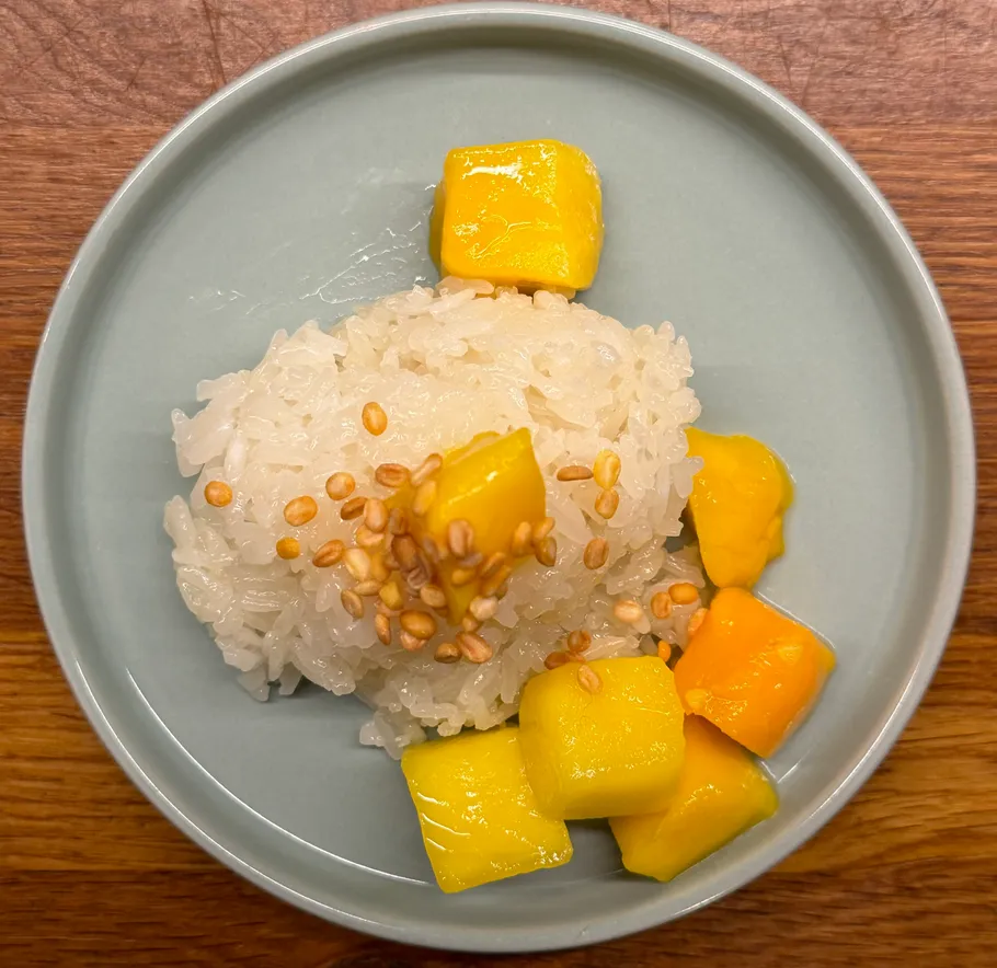 Klebreis und Mango auf blauem Teller.