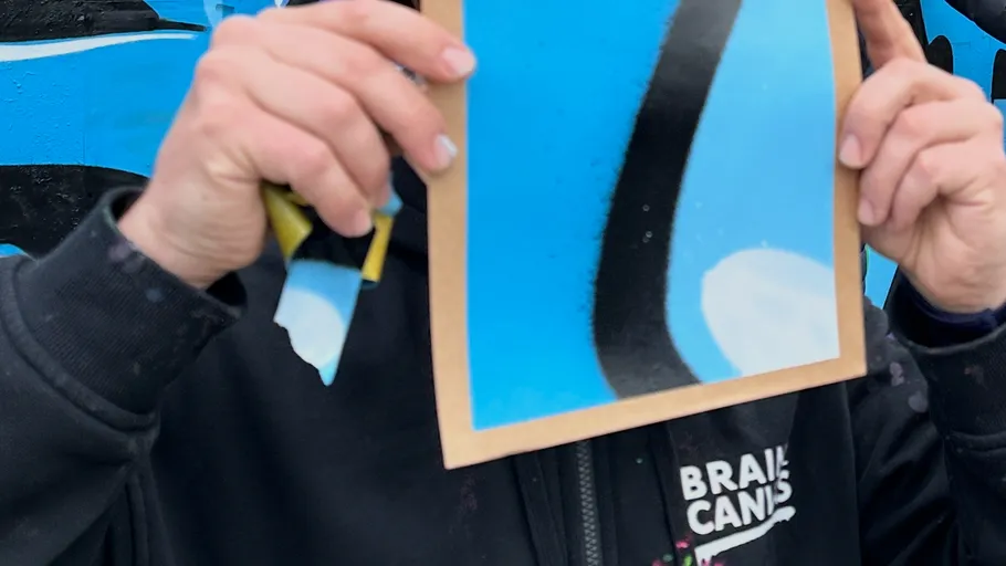 Person holding artwork with blue and black design.