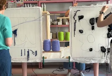 People crafting on frames in a workshop.