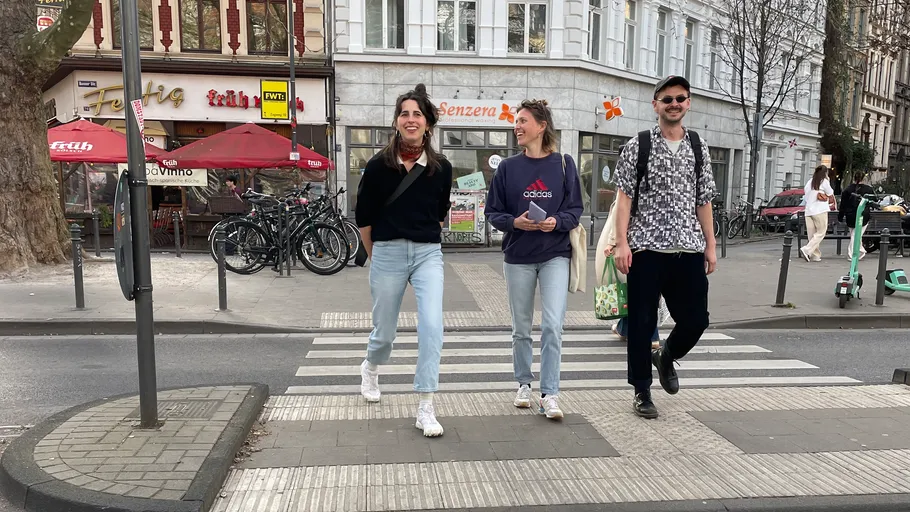 Three people walk across a city crosswalk.