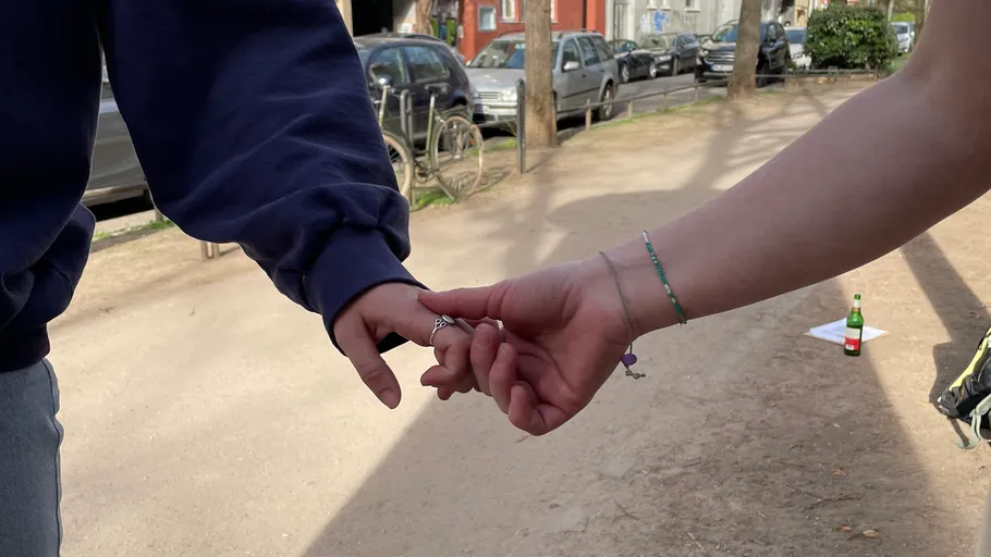 Two people holding hands on a path.