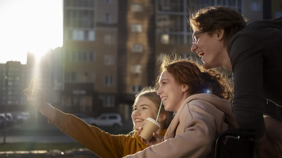 Three friends taking selfie outdoors, smiling.