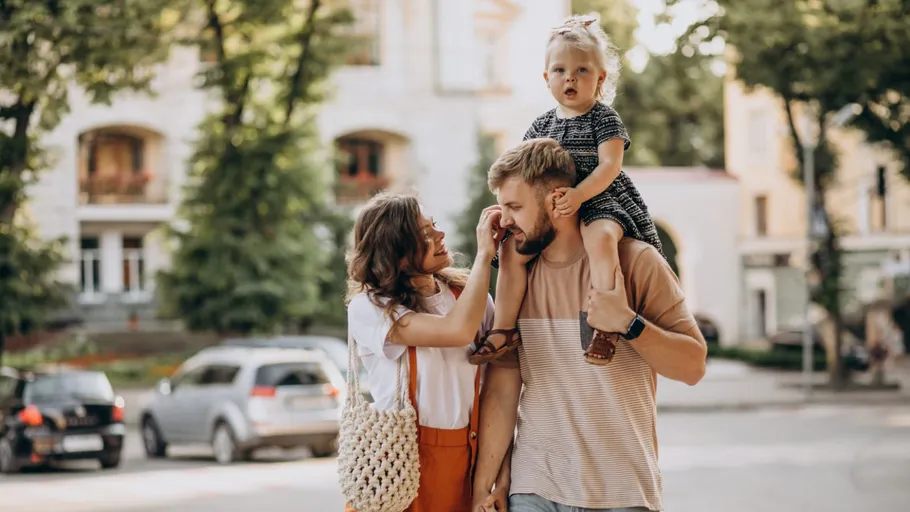 Family walking on street, child on father's shoulders.