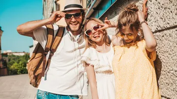 Three people smiling in sunny urban street.