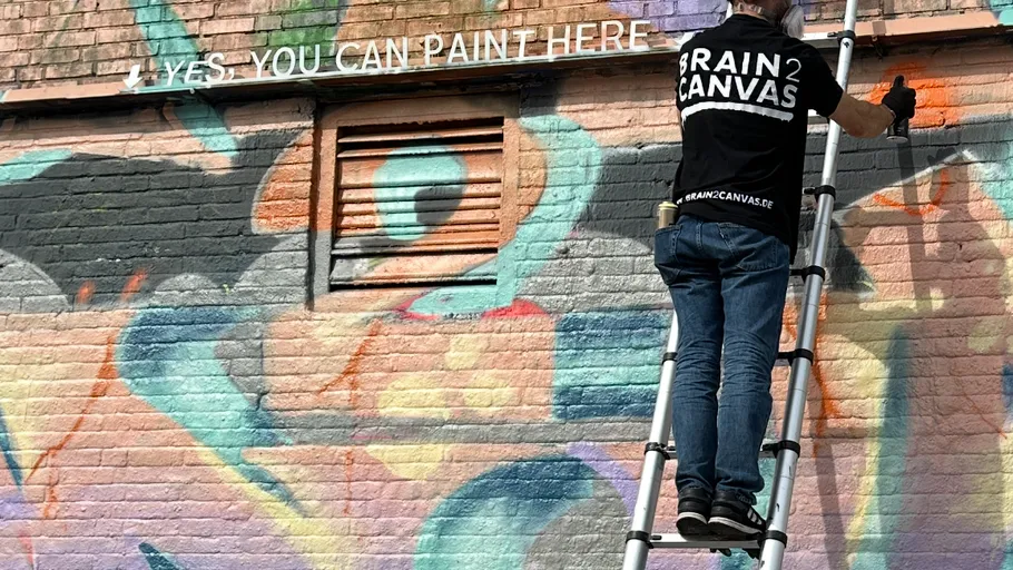 Mann malt Graffiti auf Ziegelwand.