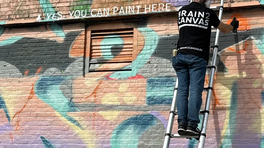 Person painting graffiti on colorful brick wall.