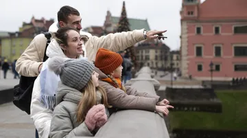 Family on bridge, pointing at historical buildings.