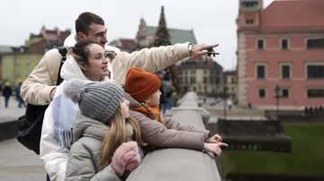 Family standing on bridge, pointing at city view.
