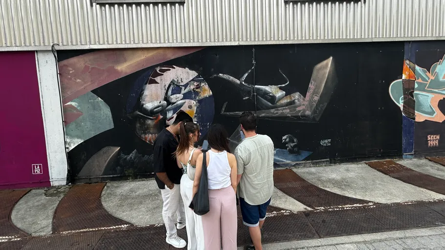 Menschen beobachten Wandgemälde in städtischer Straße.