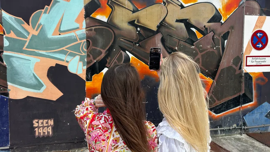Two women photographing graffiti on a wall.
