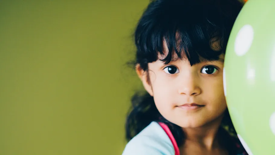 Child with balloon in indoor setting.