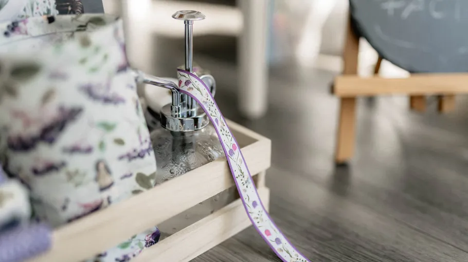 Decorative soap dispenser with floral design ribbon.