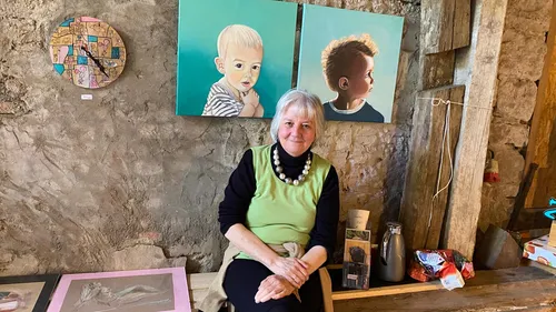 Frau sitzt in Galerie mit Gemälden.