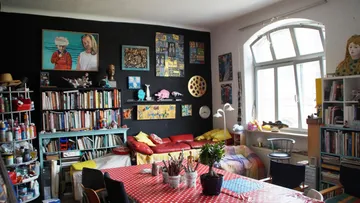 Art studio with paintings, books, and large window.