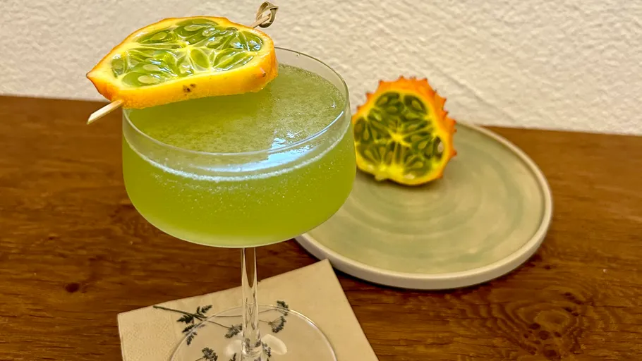 Grüner Cocktail mit Kiwano-Garnitur auf Tisch.