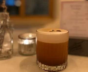 Cocktail with foam on a bar counter.