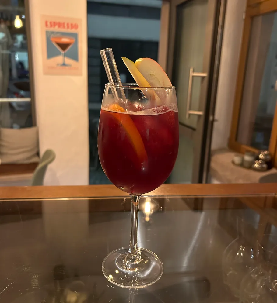 Rotes Cocktailglas mit Früchten auf dem Tisch.