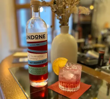 Bottle and cocktail on glass table.