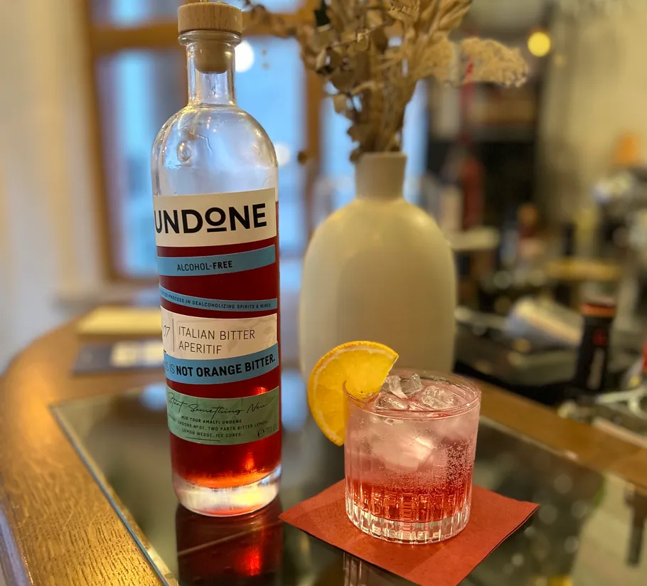 Bottle and cocktail on glass table.