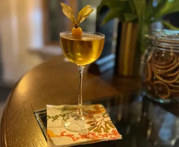 Cocktail glass with garnish on wooden table.