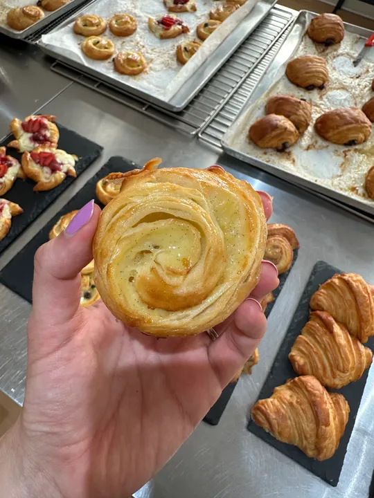 Hand hält Gebäck in einer Bäckereiumgebung.