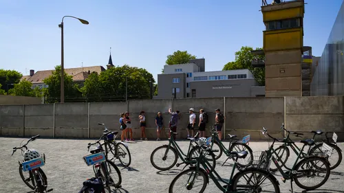People standing by Berlin Wall Memorial in summer.