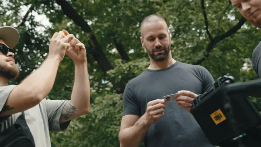 Men interacting with camera equipment outdoors.