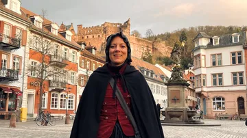 Person in cape standing in historic town square.