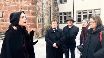 Guide speaking to group in historic courtyard.