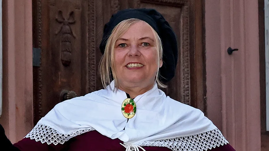 Frau in traditioneller Kleidung lächelt draußen.